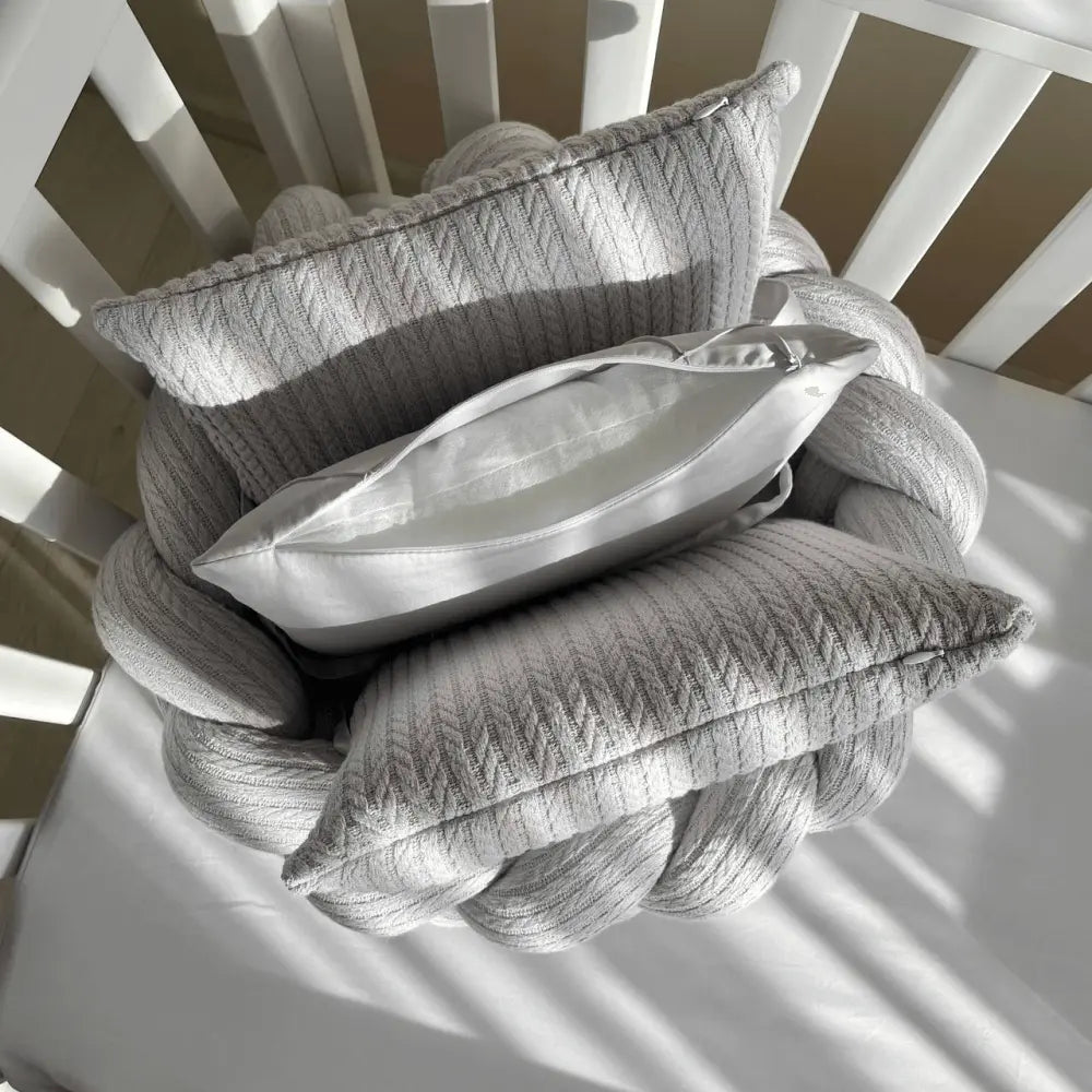 Babybettwäsche-Set 6 für 120x60 TraumLand Grau mit dekorativen Kissen in einem Babybett.